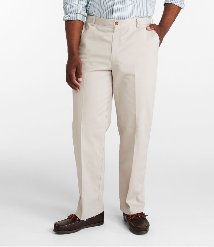Men's beige wrinkle-free chino pants with plain front, worn with a striped shirt and brown leather shoes.