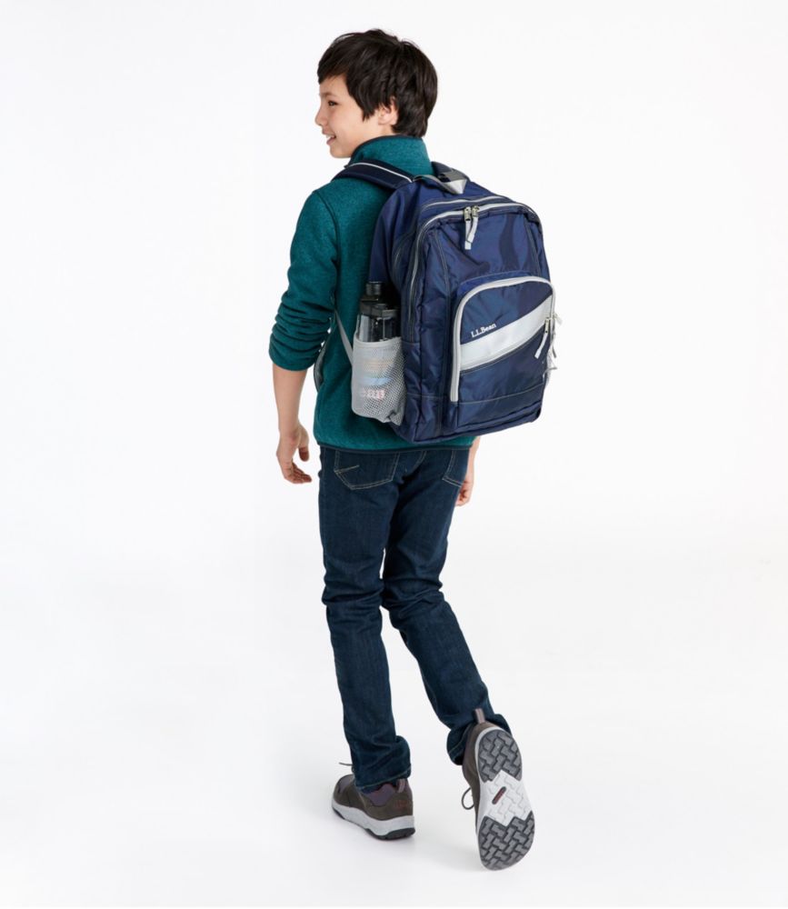 Child walking away wearing a navy deluxe backpack with gray trim and side water bottle pocket.