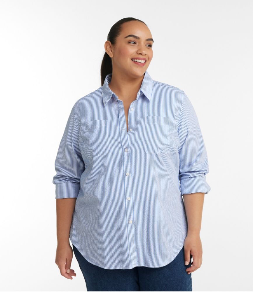 Woman wearing a blue and white striped long-sleeve seersucker button-front shirt with rolled cuffs, front view.
