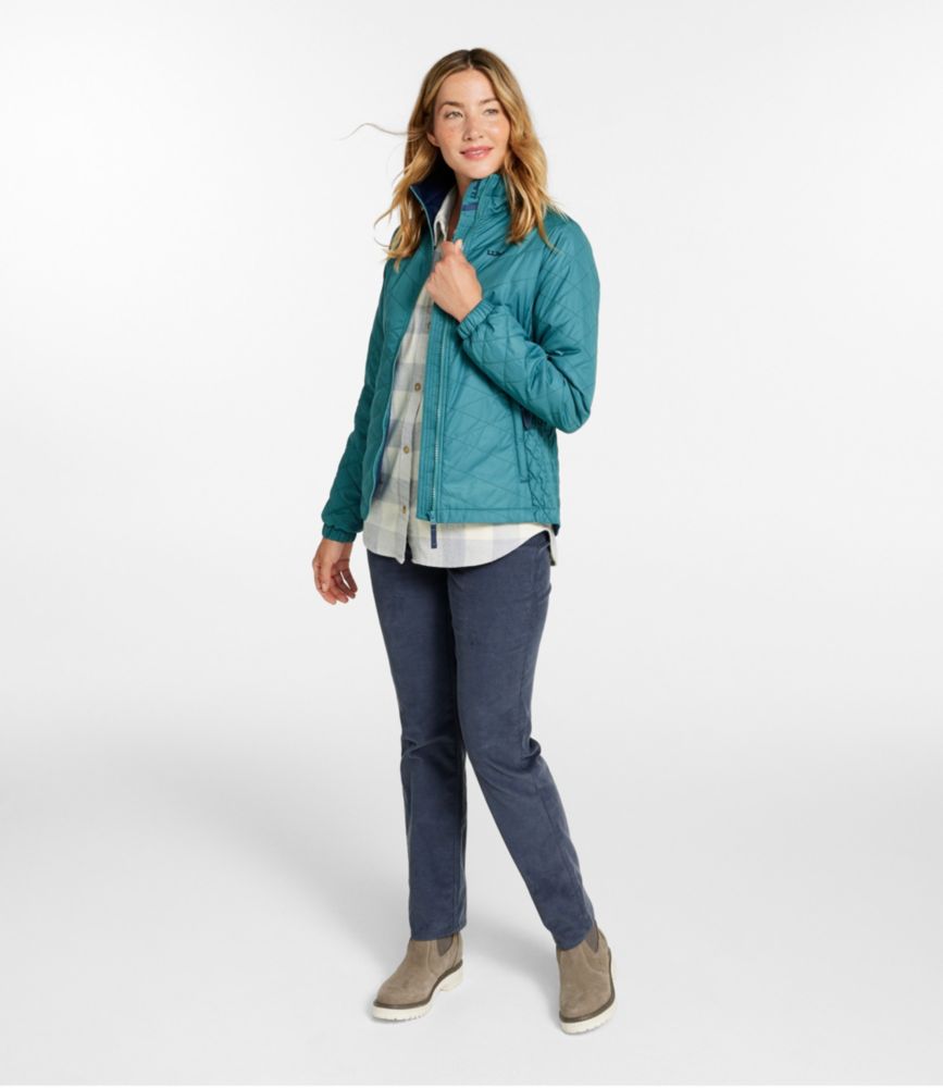 Woman wearing a teal quilted fleece-lined jacket over a plaid shirt and blue pants, standing against a white background.