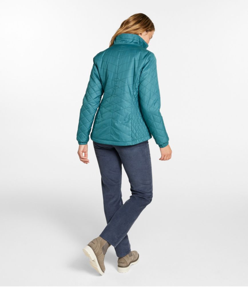 Woman shown from back wearing teal quilted fleece-lined jacket with high collar and angled stitching detail.