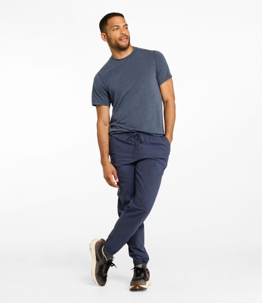 Men's blue multisport jogger pants with drawstring waist and elastic cuffs, shown worn with sneakers.