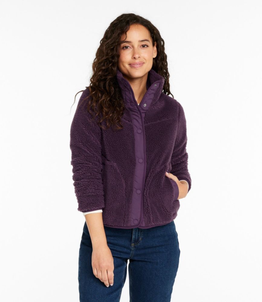 Woman wearing a purple sherpa fleece jacket with high snap collar and pockets, paired with blue jeans.