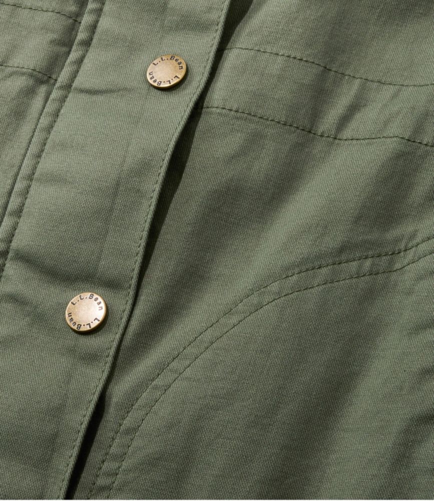 Close-up of women’s deep olive utility jacket fabric with curved seam and brass L.L.Bean snap buttons.