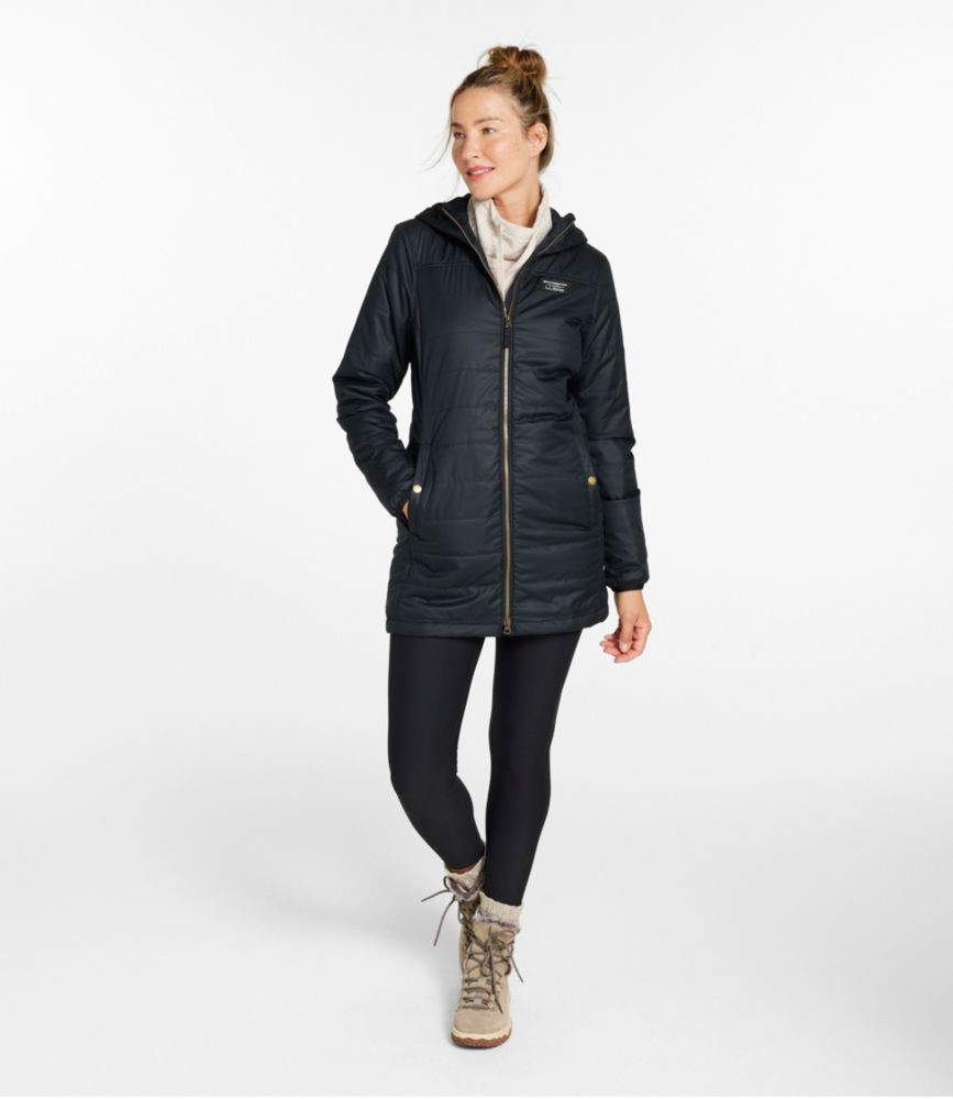 Women’s navy thigh-length quilted puffer coat with hood, front zipper and pockets, shown worn with leggings and winter boots.