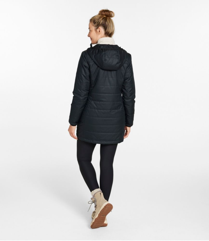 Woman shown from the back wearing a black hooded thigh-length puffer coat with quilting, leggings, and winter boots.