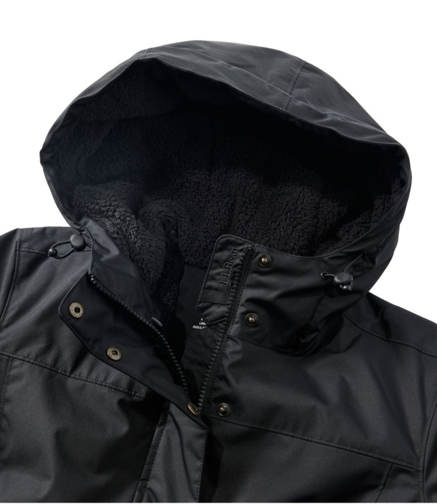 Black women’s winter coat close-up showing hood with soft fleece lining and front zipper with snap placket.