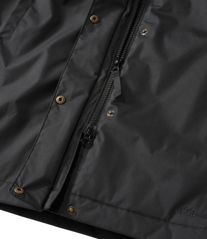 Black women’s winter coat close-up showing smooth shell fabric, front zipper, and snap-button storm flap.