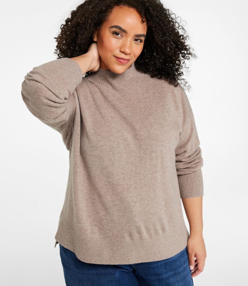 Women’s camel heather cashmere relaxed mockneck sweater worn with blue jeans, front view.