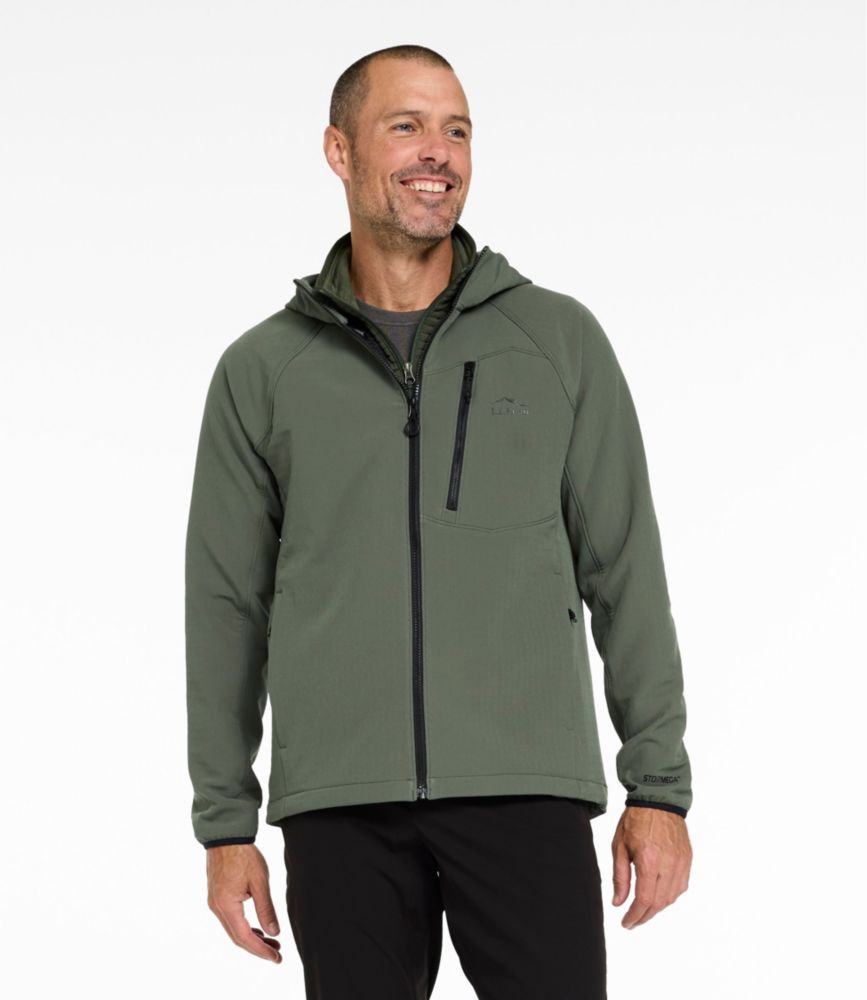 Men's thyme green softshell hoodie jacket with front zipper, chest zip pocket and hood, worn with black pants.