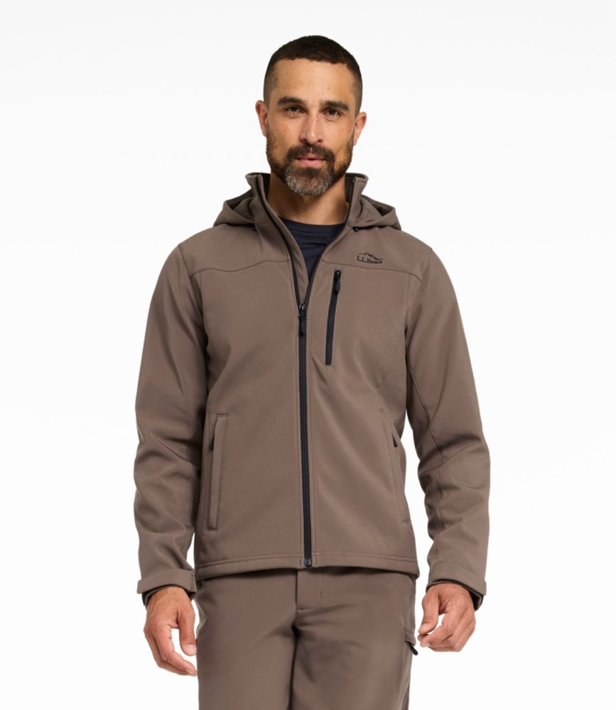 Men’s dark cinder softshell hooded jacket with full zip and zippered chest and hand pockets, worn by a standing model.