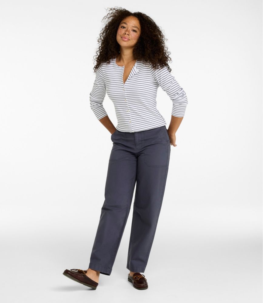 Woman wearing carbon navy mid-rise barrel-leg cotton canvas pants, standing with hands behind back.