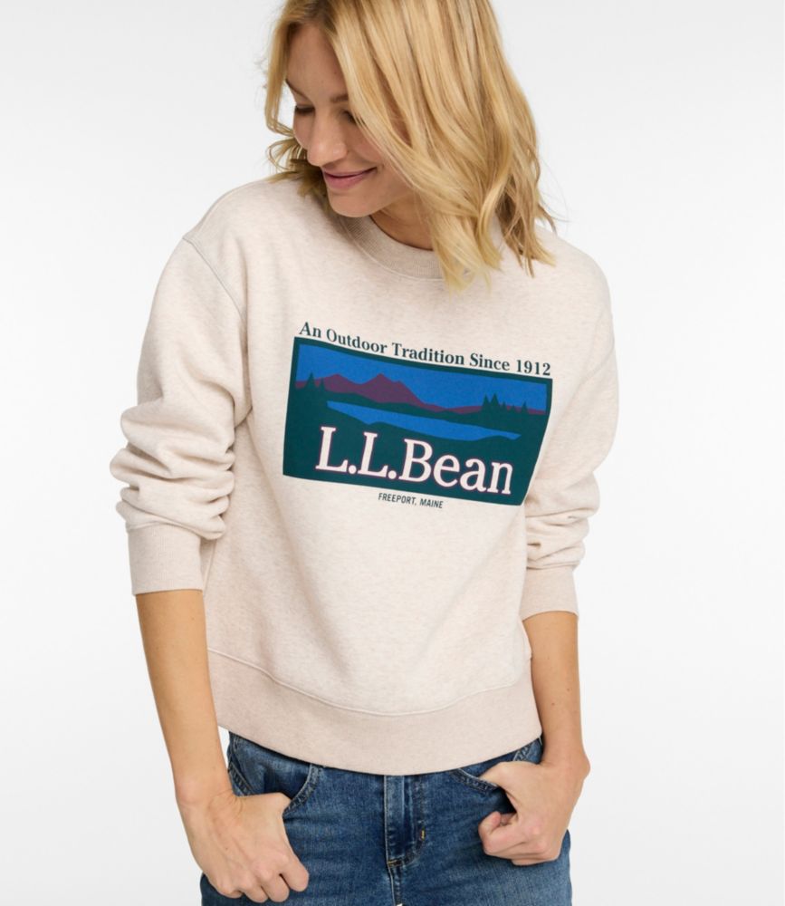 Women’s oatmeal heather crewneck sweatshirt with colorful L.L.Bean mountain graphic on chest, shown worn with jeans.
